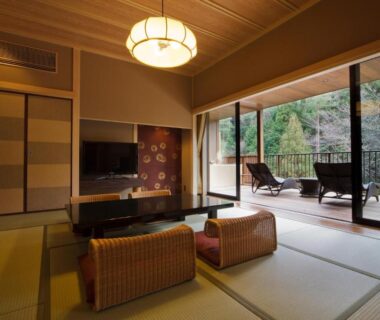 Traditional tatami room with low seating and balcony with chairs overlooking forest at Kyo Yunohana Resort Suisen Kyoto