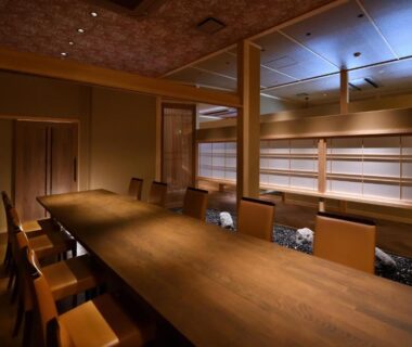 Long communal wooden dining table and chairs in warm-lit ryokan dining room at Kyo Yunohana Resort Suisen Kyoto