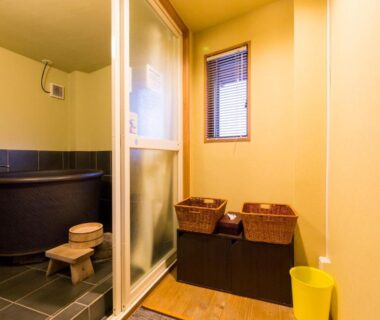 Indoor wooden soaking tub with washing stool and wicker baskets at Kyo no Yado Sangen Ninenzaka Kyoto