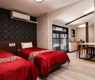 Spacious twin bedroom with red bedspreads, dining nook and modern Japanese decor at Kyomachiya Bettei Hanatei, Kyoto