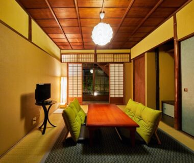 Traditional tatami room with low wooden table, green floor cushions, shoji screens and warm lantern lighting in Kyoto ryokan