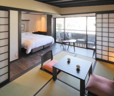 Tatami room with low table, shoji screens and bed at Kyomachiya Ryokan Sakura Urushitei in Kyoto