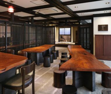 Long wooden tables and stools in communal dining area at Kyomachiya Ryokan Sakura Urushitei, Kyoto