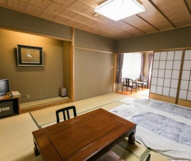 Traditional tatami room with low table, futon bedding, shoji screens and seating area at Kyonoyado Kagihei in Kyoto
