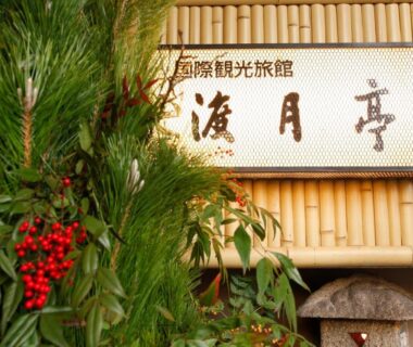 Bamboo signboard with Japanese characters, greenery and red berries at Togetsutei in Arashiyama Kyoto