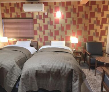 Twin beds with patterned wallpaper and seating at Kyoto Ryokan Gion Sano in Kyoto, Japan