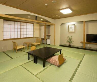 Spacious tatami room with low table, cushions, shoji screens and window seating at Kyoto Ryokan Hirashin