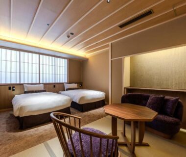 Two single beds, tatami seating area with low table, shoji window and wooden chair at Kyoto ryokan SAKANOUE