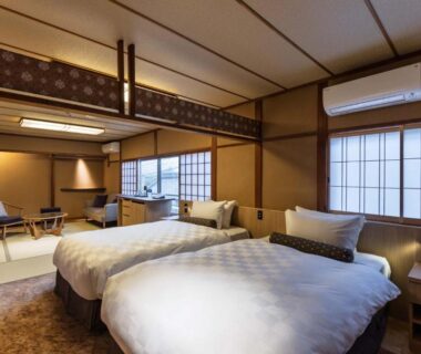 Twin beds with tatami seating area, shoji screens and wooden interior in a Kyoto ryokan room