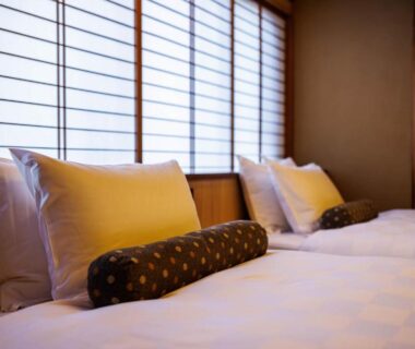Twin beds with bolster cushions and shoji screens in a serene Kyoto ryokan guest room