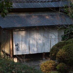 White noren curtain with kanji at Kyousen entrance surrounded by moss and trees in Nagano