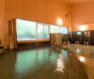 Calm indoor onsen bath with washing stations and wooden benches at Kyukamura Iwate-Amiharionsen, Iwate, Japan
