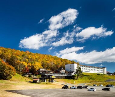 Autumn hillside ryokan building with parking area at Kyukamura Iwate-Amiharionsen in Iwate Tōhoku