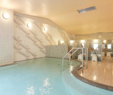Tiled communal indoor onsen with handrails and washing stations at Kyukamura Noto-Chirihama in Ishikawa