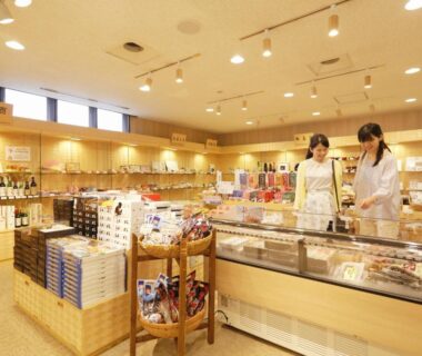 Bright souvenir shop interior with wooden displays and staff at Kyukamura Noto-Chirihama, Ishikawa