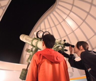 Two people using a telescope inside an observatory dome at Kyukamura Noto-Chirihama in Ishikawa