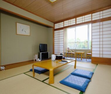 Tatami room with low table, zabuton cushions and shoji screens at Kyukamura Ohkunoshima in Hiroshima