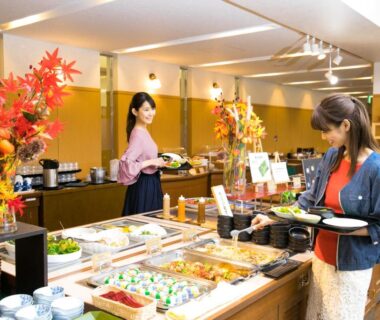 Guests selecting dishes from a buffet spread in a bright dining room at Kyukamura Ura-Bandai, Fukushima
