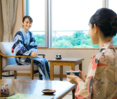 Two women in yukata sharing tea in a ryokan room at Kyukamura Ura-Bandai, Fukushima