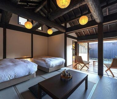 Tatami room at Kyutei with two beds, low table, exposed beams and sliding doors to a wooden deck