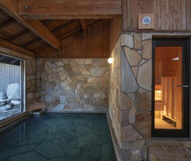 Stone-walled indoor onsen bath with window and wooden doorway at Kyutei, Kumamoto, Kyūshū