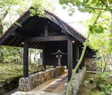 Wooden covered gateway and stone path through mossy garden at Kyutei in Kumamoto, Kyushu