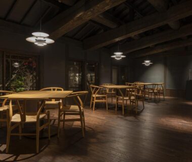 Dimly lit wooden dining room with round tables and chairs at Kyutei ryokan in Kumamoto, Kyūshū