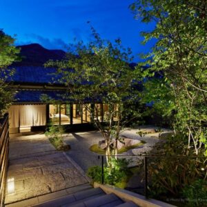 Lit courtyard with stone steps, bamboo fence and traditional wooden ryokan entrance in Shizuoka, Chūbu