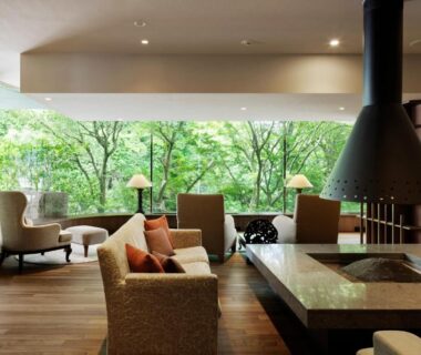 Lounge with sofa seating, suspended fireplace and floor-to-ceiling windows overlooking lush greenery at Laforet Hakone Gora Yunosumika