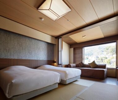Japanese-style room with tatami flooring, twin Western beds, low sofa and large window overlooking greenery