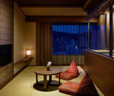 Tatami seating area with low table and distant city view at Laforet Ito Onsen Yunoniwa in Shizuoka