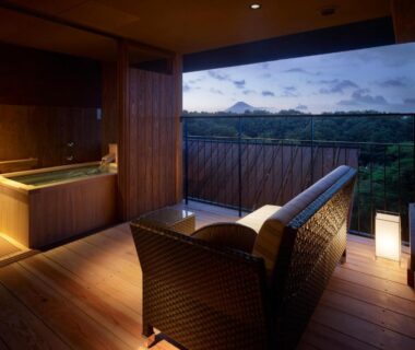 Wooden deck with tub and wicker sofa at Laforet Shuzenji Sanshisuimei in Shizuoka mountain view