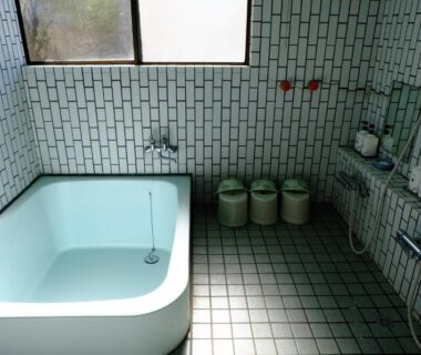 Tiled bathing area with bathtub and wall shower at Lake Oshino ryokan, Yamanashi, Chūbu, Japan
