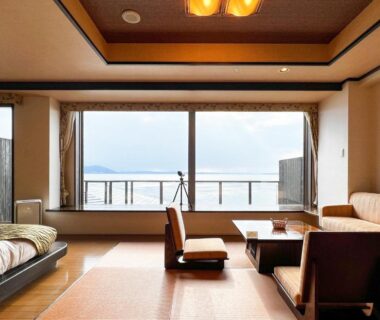 Japanese tatami room with low table, sofa and bed facing Lake Saroma through large window