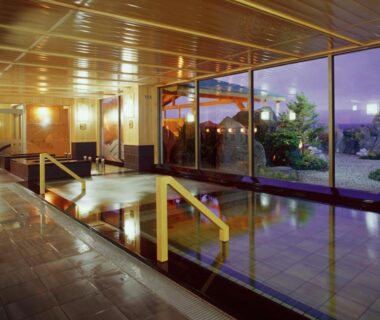 Spacious indoor onsen with wooden ceiling, tiled bath and garden view at Lake Saroma Tsuruga Resort Hokkaidō