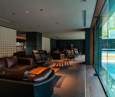 Leather sofas and chairs in a glass-walled lounge overlooking an outdoor pool at Lake Shikotsu Tsuruga Bessou AO no ZA