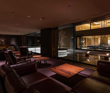 Low seating lounge with upholstered sofas, wooden tables and floor-to-ceiling windows at Lake Shikotsu Tsuruga Bessou AO no ZA