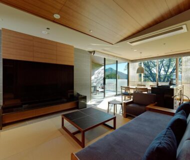 Spacious lounge with sofa, low table and floor-to-ceiling windows at Lake Shikotsu Tsuruga Bessou AO no ZA Hokkaidō