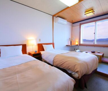 Twin beds with raised tatami seating and large window at Lake Side Hotel Minatoya Fukushima