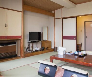 Traditional tatami room with low table, zabuton chairs and TV at Lake Side Hotel Minatoya in Fukushima