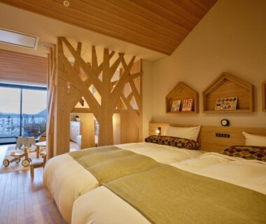 Twin beds with wooden tree partition, children's play area and balcony in Lake Toya Tsuruga Resort HIKARINOUTA, Hokkaidō