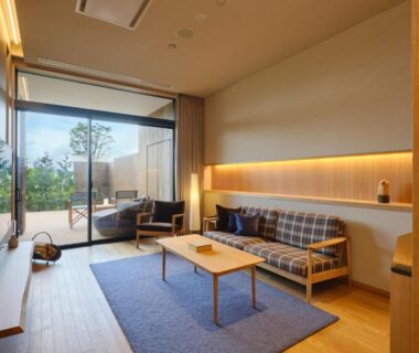Bright guest living area with sofa, low table, TV and sliding glass door to garden terrace