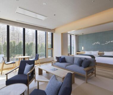 Bright room with sofa, low tables, twin beds and floor-to-ceiling garden windows at Lake Toya Tsuruga Resort Hokkaidō