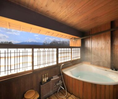 Indoor wooden bath with large window overlooking mountains at Lakeland Hotel Mizunosato, Chūbu Yamanashi