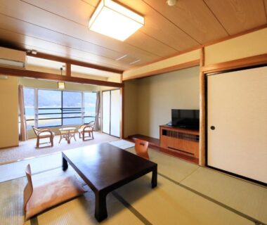 Traditional tatami room with low table, sliding doors and balcony overlooking lake in Yamanashi