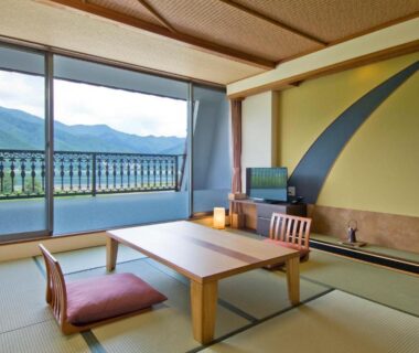 Traditional tatami room with low table, cushions, and balcony overlooking mountains in Yamanashi