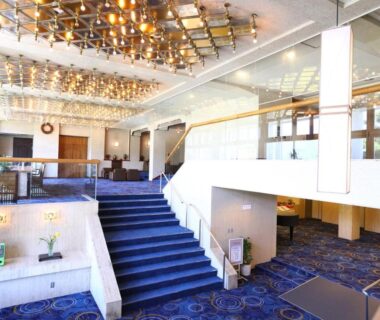 Hotel lobby with carpeted staircase, chandeliers, check-in desk and seating at Lakeland Hotel Mizunosato, Yamanashi