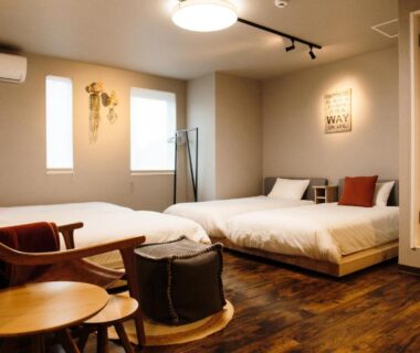 Modern twin room with wooden floor, two low beds and lounge chairs at Lampstand STAY Asahikawa, Hokkaidō