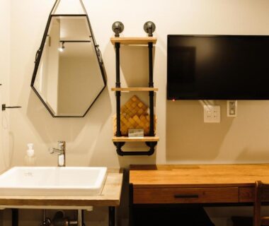 Modern vanity with rectangular sink, geometric mirror, wooden desk and wall-mounted TV at Lampstand STAY Asahikawa, Hokkaidō room