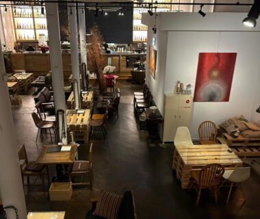 Warm wooden tables, eclectic seating and pendant lights at Lampstand STAY Asahikawa lounge, Hokkaidō